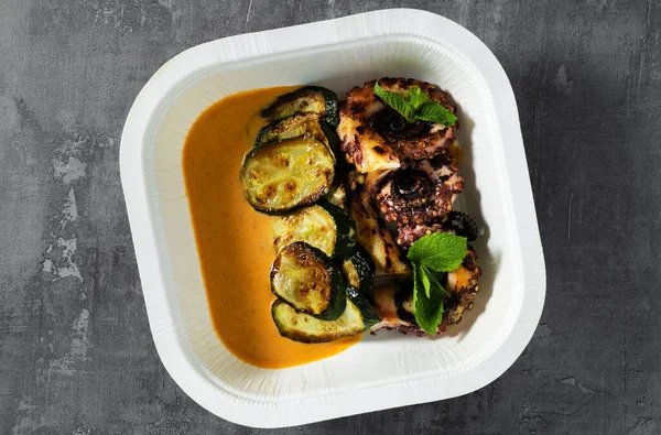 cooked octopus, served with courgettes and sauce in a box for delivery