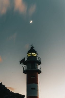Deniz feneri olan bir adada gün batımı