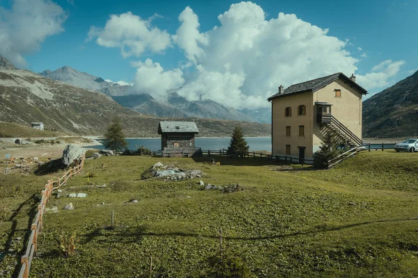 Mountain cloudscape with houses next to a lake