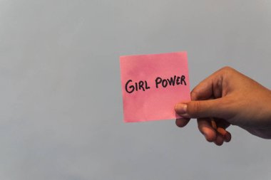 Pembe feminist posterleri gösteren bir el.