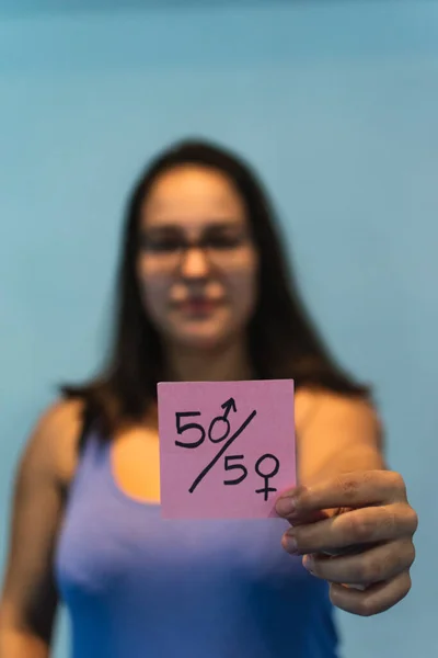 Arka planda elinde pembe feminist posterleri tutan bir kız.