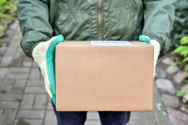 Postacının elindeki karton kutu. Paket kurye servisinin evinize teslimatı. Ögeler kurye ile gönderiliyor.