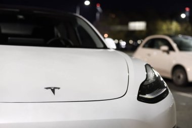 Tesla Motors şirketinin beyaz elektrikli arabası. Elektrikli arabanın ön kaputunda Tesla şirketi logosu: Riga, Letonya - 22 Eylül 2021.