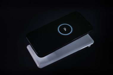 Siyah arkaplandaki şarj cihazından kablosuz şarj olurken akıllı telefon