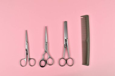 Hairdressing tools comb and different scissors on pink background
