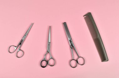 Berber için farklı bir makas seti. Pembe arka planda kuaför, tarak ve farklı makas araçları.