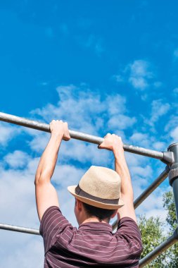 Barın arkasında duran genç bir adam gökyüzüne doğru yanaşıyor, boşluğu kopyalıyor. Hipster ya da inek dışarıda egzersiz yapıyor..