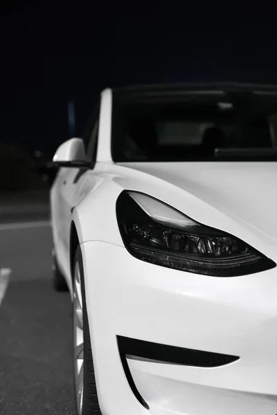 Tesla Motors şirketinin ön far, tampon ve dış farı geceleyin beyaz elektrikli araba Riga, Letonya - 22 Eylül 2021