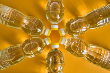 Turuncu arka planda doğal rafine ayçiçeği yağıyla plastik şişelerin üst görüntüsü