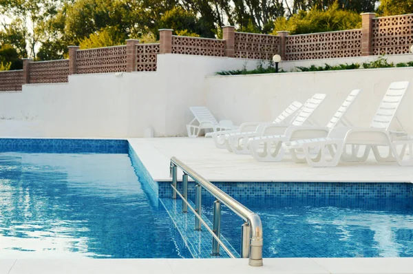 Mavi temiz suyu olan yüzme havuzu dinlenmek için dinlenmek için arka planda dinlenmeye hazır dinlenme tesisinde dinlenmek için.