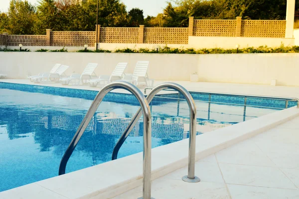 Arka planda parmaklıklar olan yüzme havuzu tatil köyünde dinlenmek için dinlenme yeri.