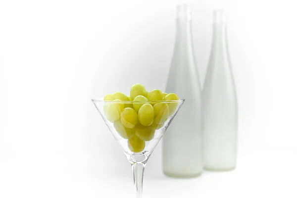 在模糊的空酒瓶的背景下 有葡萄的酒杯 — 图库照片
