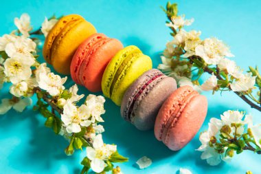 Mavi arka planda çiçekli renkli badem kurabiyeleri