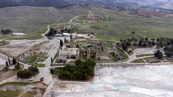 Pamukkale Travertines Türkiye, antik kaplıca kenti Hierapolis 'in beyaz kireçtaşı şehir silueti kalıntılarına tepeden bakıyor