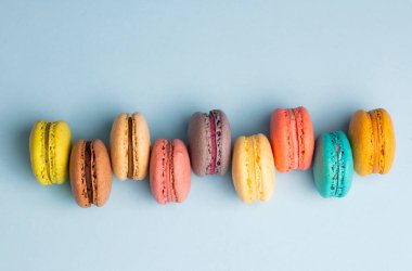 Colorful macaroon cakes. Small french muffins. Colorful macarons on a blue background