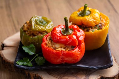 Doldurulmuş biber, pirinçle doldurulmuş yarım biber, kurutulmuş domates, otlar ve peynir mavi ahşap bir masada fırın kabında, üst manzara. (Türkçe adı; biber dolmasi)
