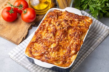 Eritilmiş mozzarella peyniri ile kaplı makarna güveç sosu ve bir masada beyaz bir fırın kabında servis edilir (Türk adı; firinda makarna veya firin makarna)