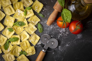 Delicious raw ravioli with flour and basil on dark background. The process of making Italian ravioli.