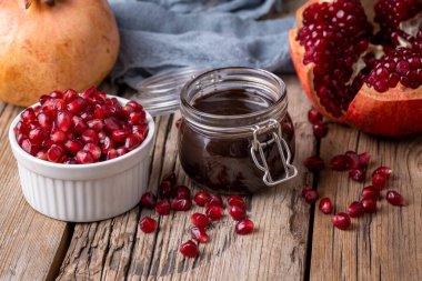 Glass bottle of pomegranate sour sauce with fresh ripe whole and split pomegranate fruit (Turkish name; nar eksisi)