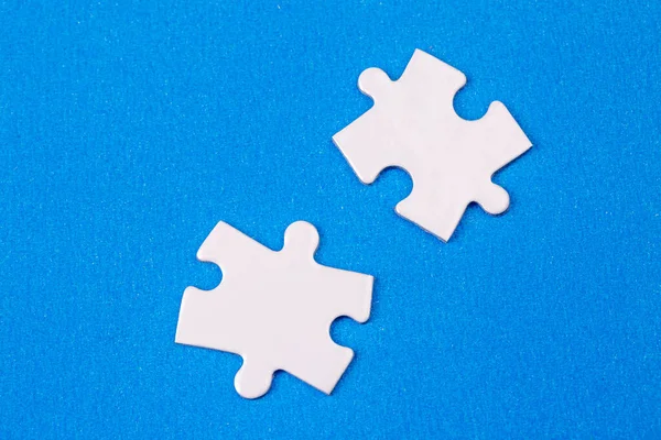 Missing jigsaw puzzle pieces. Business concept. Fragment of a folded white jigsaw puzzle and a pile of uncombed puzzle elements against