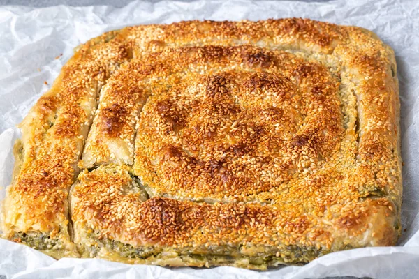 Greek cuisine dishes; spanakopita Sesame on handmade spinach feta cheese pie in the oven. Turkish name; ispanakli borek