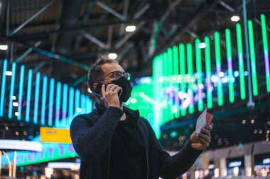 Moskova Sheremetyevo - 3 Ocak 2022: inek bir adamın portresi. Havaalanının kapısına yakın bir uçuşta maske takan bir turist. Coronavirus gribi virüsü seyahati