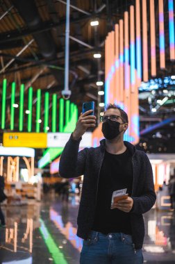 Moskova Sheremetyevo - 3 Ocak 2022: inek bir adamın portresi. Havaalanının kapısına yakın bir uçuşta maske takan bir turist. Coronavirus gribi virüsü seyahati