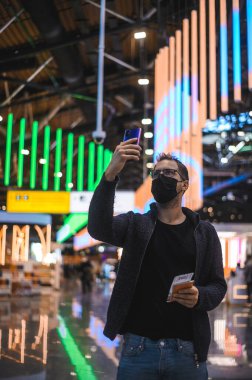 Moskova Sheremetyevo - 3 Ocak 2022: inek bir adamın portresi. Havaalanının kapısına yakın bir uçuşta maske takan bir turist. Coronavirus gribi virüsü seyahati