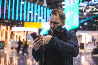 Moskova Sheremetyevo - 3 Ocak 2022: inek bir adamın portresi. Havaalanının kapısına yakın bir uçuşta maske takan bir turist. Coronavirus gribi virüsü seyahati