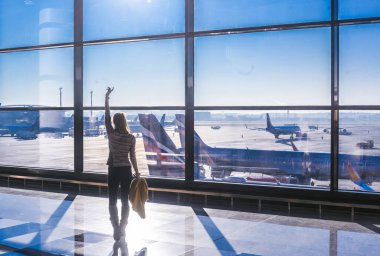 Moskova Sheremetyevo - 3 Ocak 2022: Kız silueti. Havaalanının kapısına yakın bir uçuşta maske takan bir turist. Coronavirus gribi virüsü seyahati