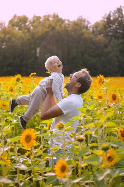 happy fatherhood in the sunflower field. son and father with glasses