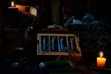 Sihirli özellikleri olan karanlık bir sahne mavi ve kırmızı sıvıyla dolu cam şişelerle dolu tahta bir kutuya odaklanmış..