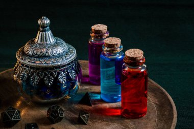 Sihirli iksirlerin resmi ve tahta tabakta RPG zarları olan bir cam kap.