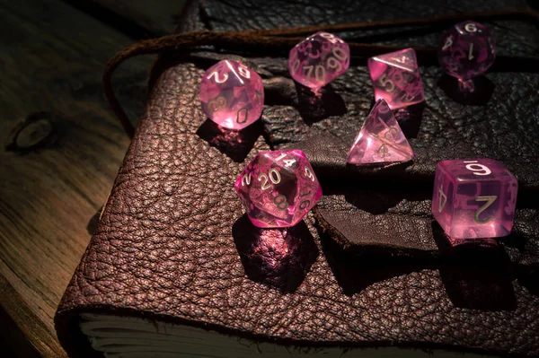 Deri kaplı bir defterde pembe şeffaf RPG zarlarının görüntüsü
