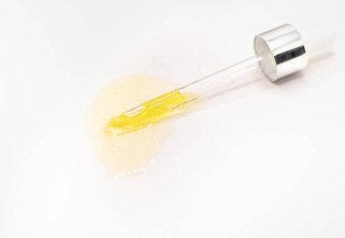 Beyaz arkaplandaki yüz serumuna yakın plan. Kolajen, deri bakımı için hiyalürik asit. Beyaz bir yüzey üzerinde altın serumla pipette