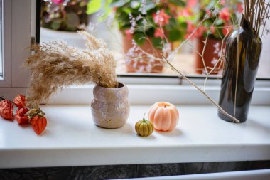Cadılar Bayramı hazırlıkları, balkabağı şeklinde mumlar ve pencere kenarında kuru bir buket olan vazo Cadılar Bayramı ve Anma Günü 'nün atmosferi, mumlardan oluşan samimi bir kompozisyon..