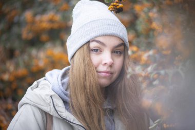 Sarı Rowan 'ın donmuş dallarının arkasında bir kadının portresi, sarı böğürtlenlerin arkasında sarışın, güzel genç bir kadın.