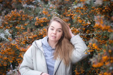 Sarı Rowan 'ın donmuş dallarının arkasında bir kadının portresi, sarı böğürtlenlerin arkasında sarışın, güzel genç bir kadın.