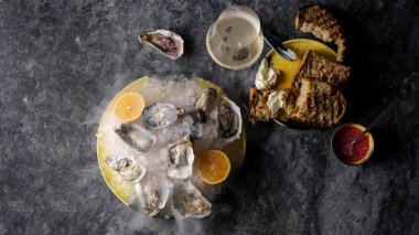Limonlu istiridye, sos, tartin ekmeği ve tereyağı, köpüklü şarap. Mermer arka plan. Üst görünüm, yatay