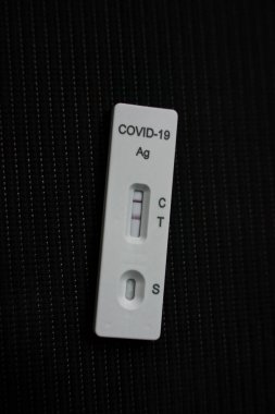 A positive Covid 19, SARS CoV 2, Corona antigen test kit for self testing, one step coronavirus antigen rapid test, close up with dark background