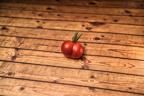 A heart or butt shaped red tomato on a wooden background