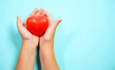 Mavi arka planda kalbi tutan kadın elleri