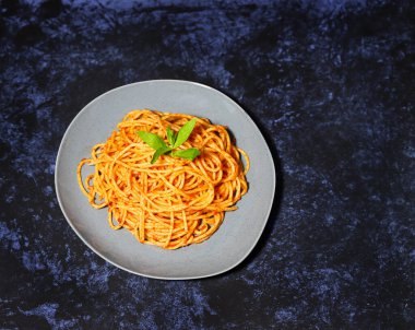 Domates soslu spagetti ve bir tabak fesleğen.