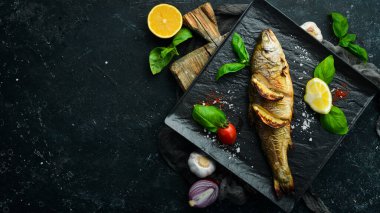 Siyah taş tabakta limonlu ve sebzeli fırında alabalık. Deniz ürünleri. Nehir balığı. Üst görünüm.