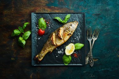Siyah taş tabakta limonlu ve sebzeli fırında alabalık. Deniz ürünleri. Nehir balığı. Üst görünüm.