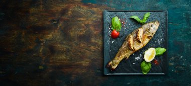 Siyah taş tabakta limonlu ve sebzeli fırında alabalık. Deniz ürünleri. Nehir balığı. Üst görünüm.