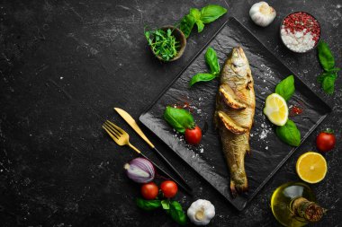 Siyah taş tabakta limonlu ve sebzeli fırında alabalık. Deniz ürünleri. Nehir balığı. Üst görünüm.