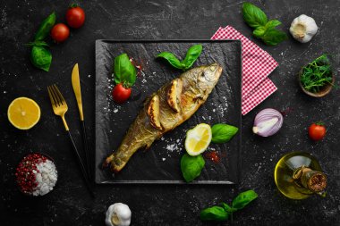 Siyah taş tabakta limonlu ve sebzeli fırında alabalık. Deniz ürünleri. Nehir balığı. Üst görünüm.