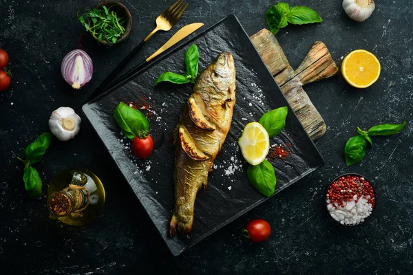 Siyah taş tabakta limonlu ve sebzeli fırında alabalık. Deniz ürünleri. Nehir balığı. Üst görünüm.
