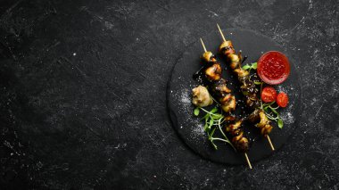 Siyah taştan bir tabakta sebzeli Rapana şişleri. Restoran yemeği. Deniz ürünleri. Kırsal tarzda. Düz Yat.